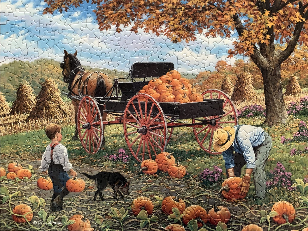 A horse-drawn wagon loaded with pumpkins in an autumn field with a man, a boy, and a dog.