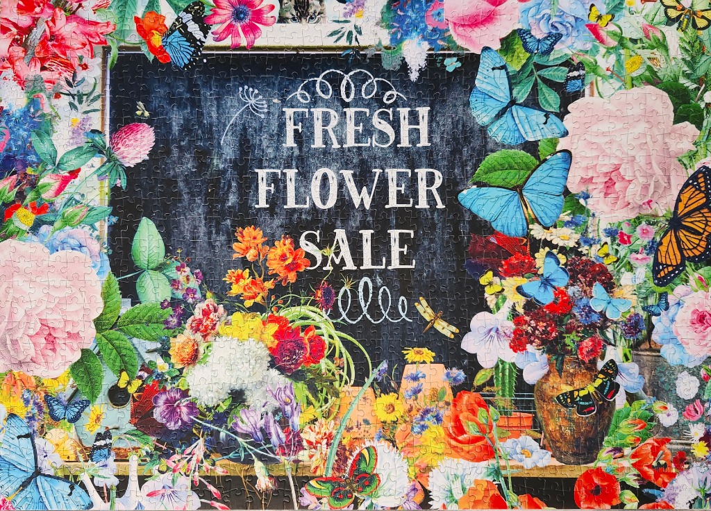 A chalkboard sign reading Fresh Flower Sale surrounded by colorful blooming flowers and butterflies.