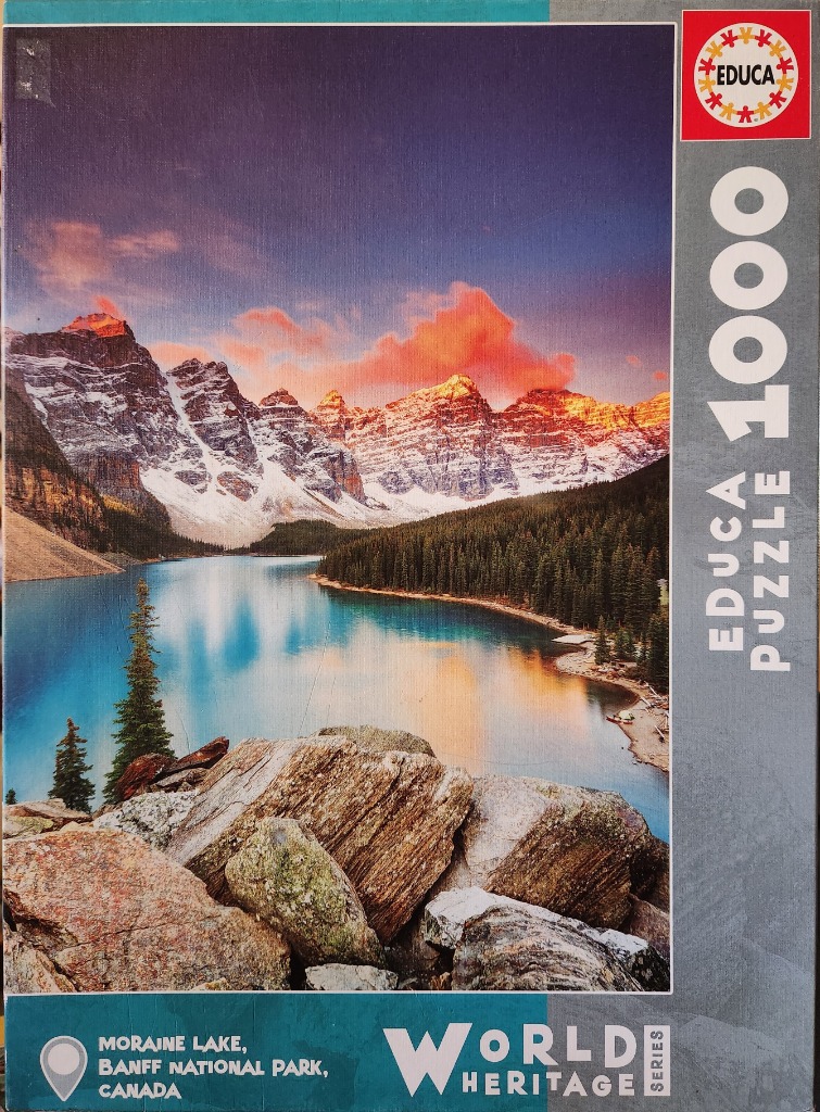 A scenic photograph of Moraine Lake at sunrise, with snow-capped mountains reflecting in bright turquoise water.