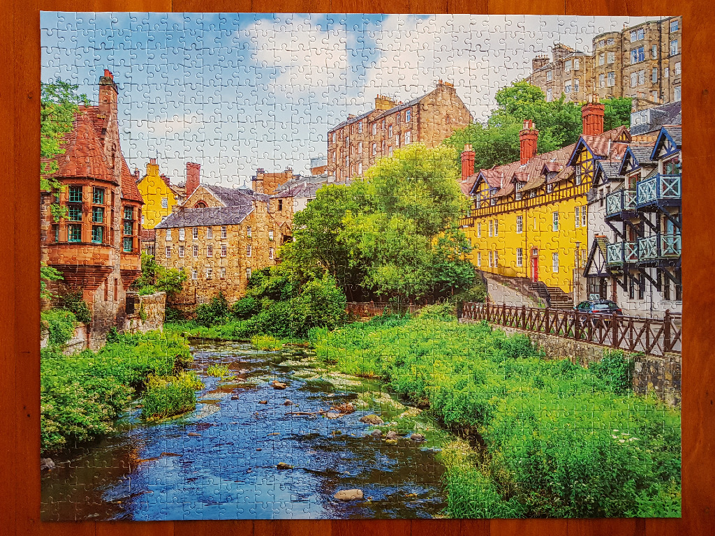 A picturesque European town nestled along a flowing river with historic stone and yellow buildings.