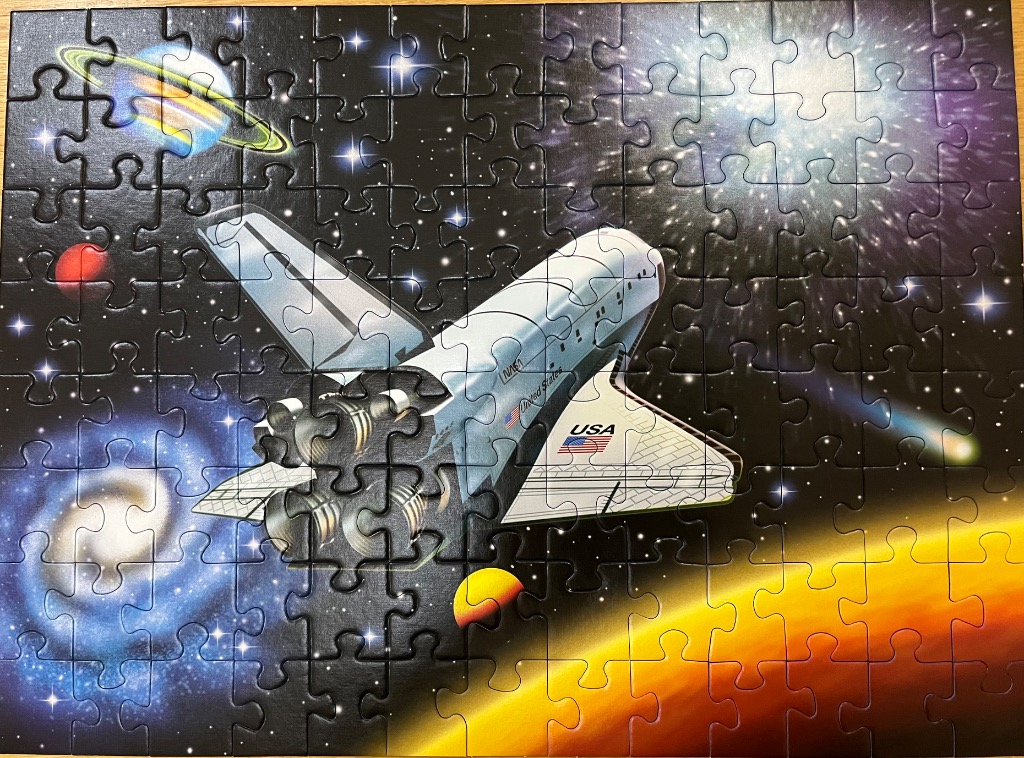 A space shuttle flying through deep space past a ringed planet, galaxy, and a glowing orange horizon.