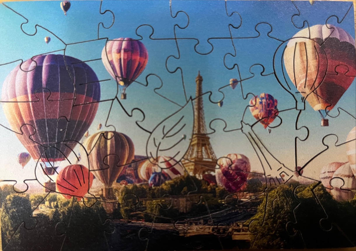 Hot air balloons floating over Paris with the Eiffel Tower in the background.