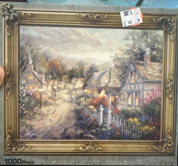 A peaceful village scene with stone cottages, a dirt path, and lush gardens inside an ornate gold frame.