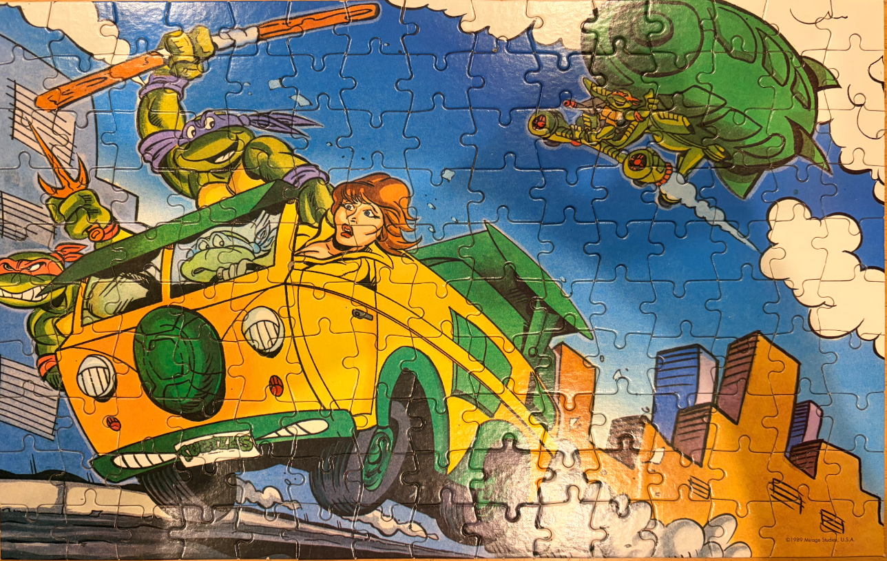 Illustration of the Teenage Mutant Ninja Turtles driving a yellow van while being chased by an aerial craft.