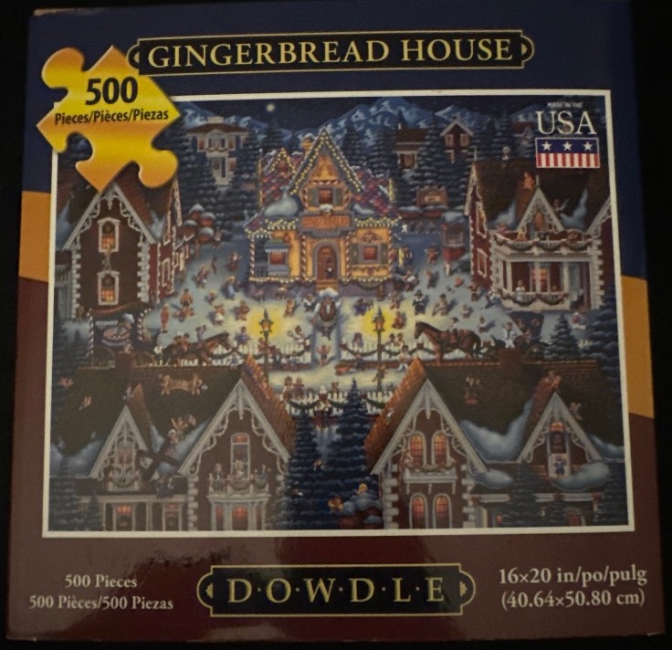 A night scene of a festive gingerbread-style village in the snow with crowds of people and warm lights.