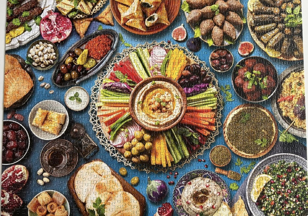 An overhead view of a diverse Middle Eastern feast with a central hummus platter and various side dishes.