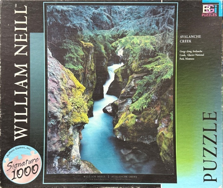 A lush, narrow gorge featuring a bright, turquoise-blue stream flowing between moss-covered rock walls and evergreen trees.