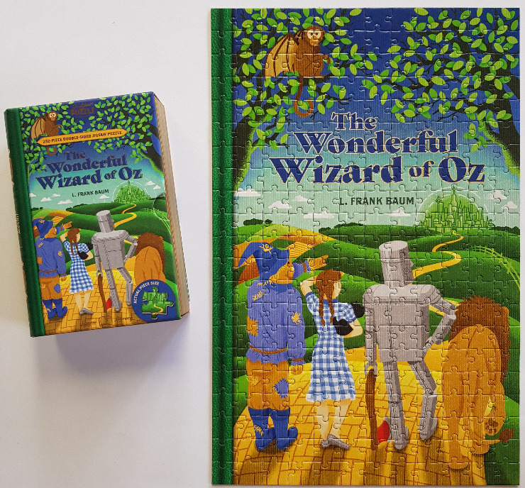 Book cover illustration of The Wonderful Wizard of Oz featuring Dorothy, the Scarecrow, Tin Man, and Lion on a yellow road.