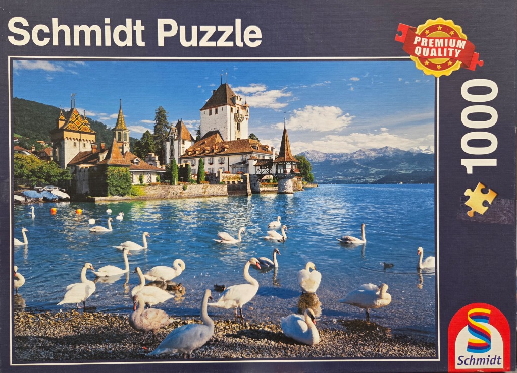 A flock of swans in front of a white castle on the shores of Lake Thun in Switzerland.