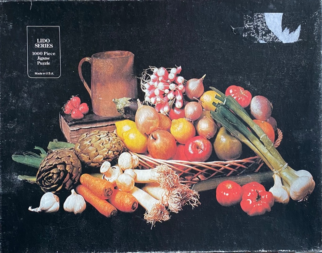 A still life photograph of fresh vegetables and fruit in a wicker basket against a dark background.