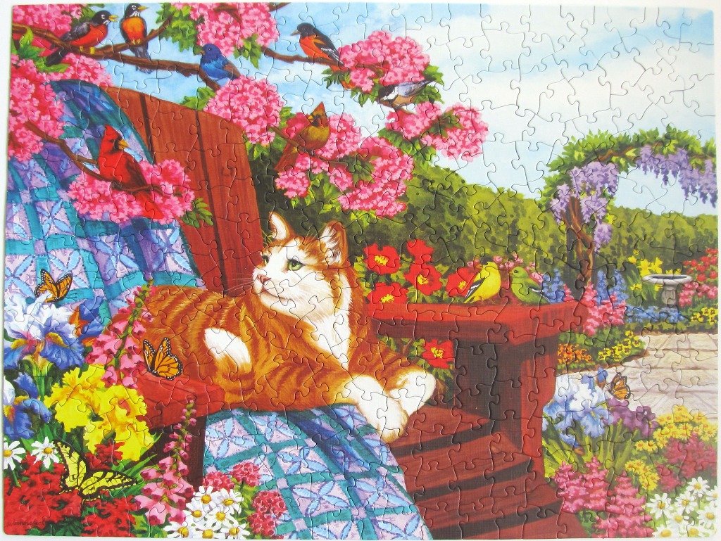 An orange tabby cat resting on a red deck chair surrounded by a vibrant spring garden filled with flowers and birds.