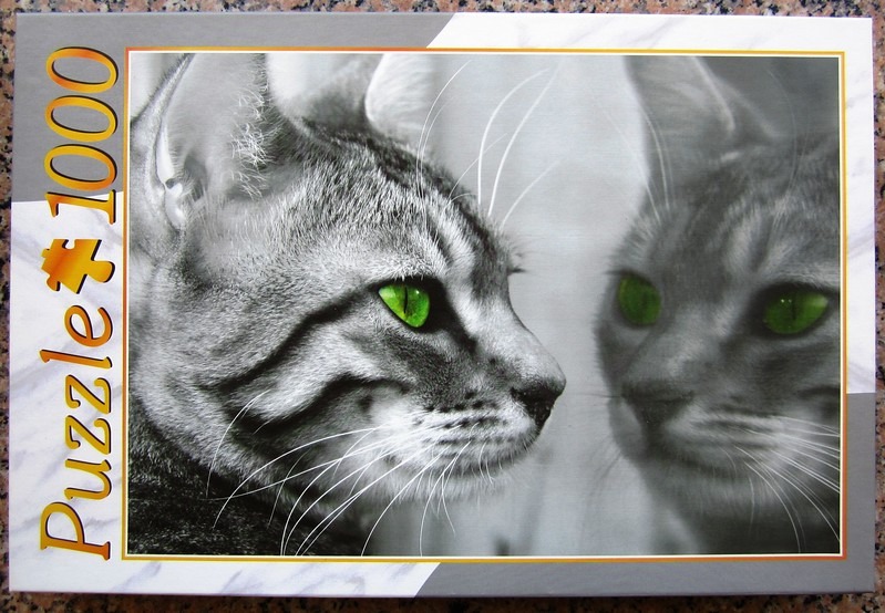 A black and white photograph of two cats facing each other with bright green eyes.