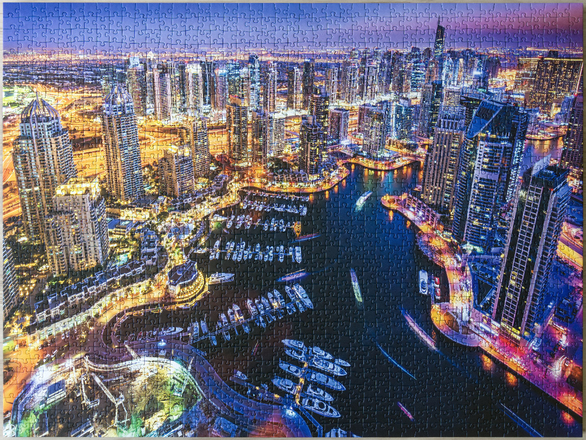 Aerial view of Dubai Marina at twilight with illuminated skyscrapers and yachts in the water.