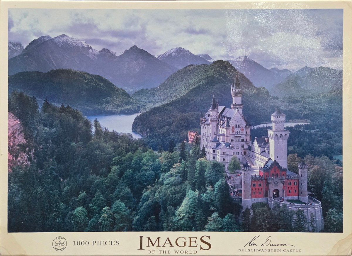 A scenic, high-angle photograph of Neuschwanstein Castle nestled in a lush, mountainous Bavarian landscape.