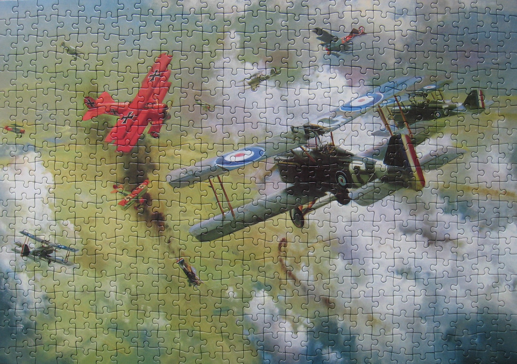 A World War I aerial dogfight featuring a bright red triplane and several biplanes in a cloudy sky.