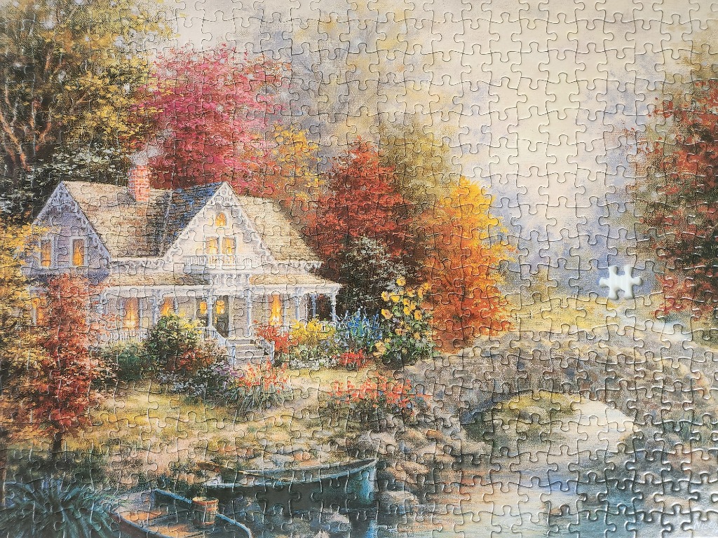 A Victorian-style cottage beside a river in an autumn forest setting