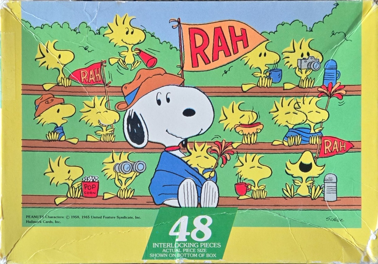 Snoopy and a crowd of Woodstock birds cheering in bleachers with flags, pom-poms, and snacks.