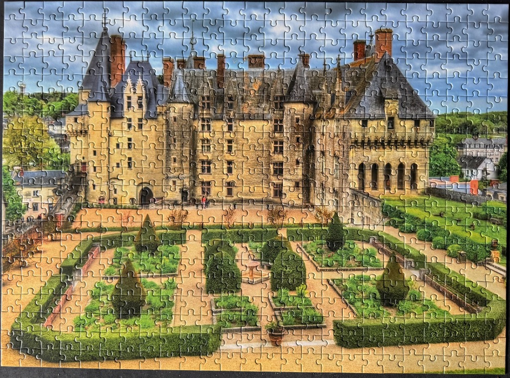 A photograph of a grand French castle behind a symmetrical manicured garden.