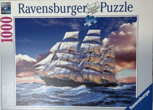 A tall ship with full white sails navigating choppy deep blue ocean waves under a dramatic sunset sky.