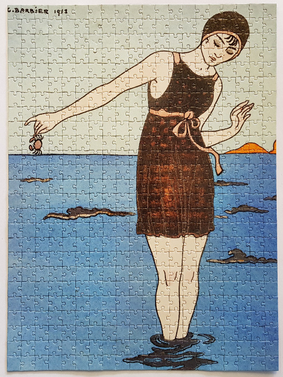 Vintage 1913 illustration of a woman in a dark swimsuit holding a crab at the seaside.