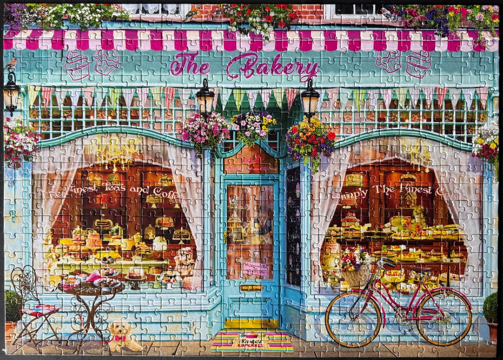 A charming bakery storefront with a pink striped awning, flower baskets, and a bicycle out front.