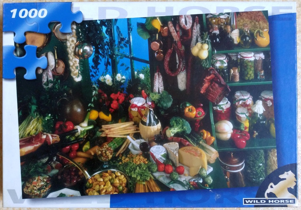 A kitchen still life featuring assorted cured meats, cheeses, fresh vegetables, and jars of preserved foods.