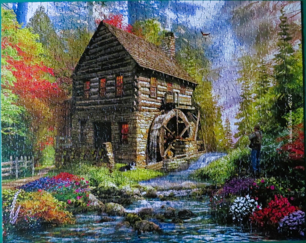 A scenic painting of a rustic log watermill nestled in a vibrant autumn forest with a fisherman and his dog nearby.