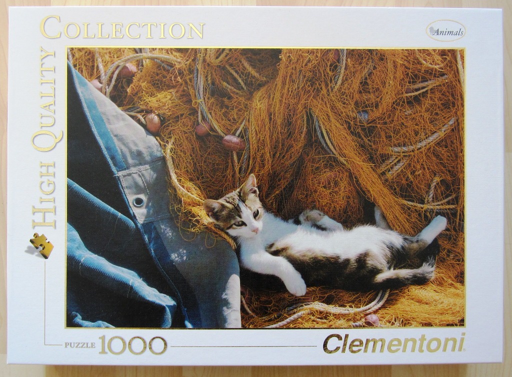 A cat lying on its back in a pile of golden-orange fishing nets next to a blue canvas bag.
