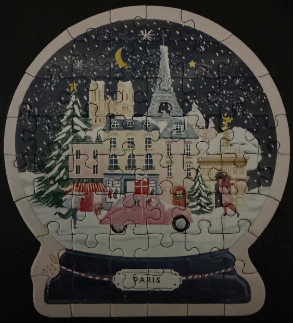 A whimsical snow globe illustration featuring a snowy Parisian street scene with the Eiffel Tower at night.