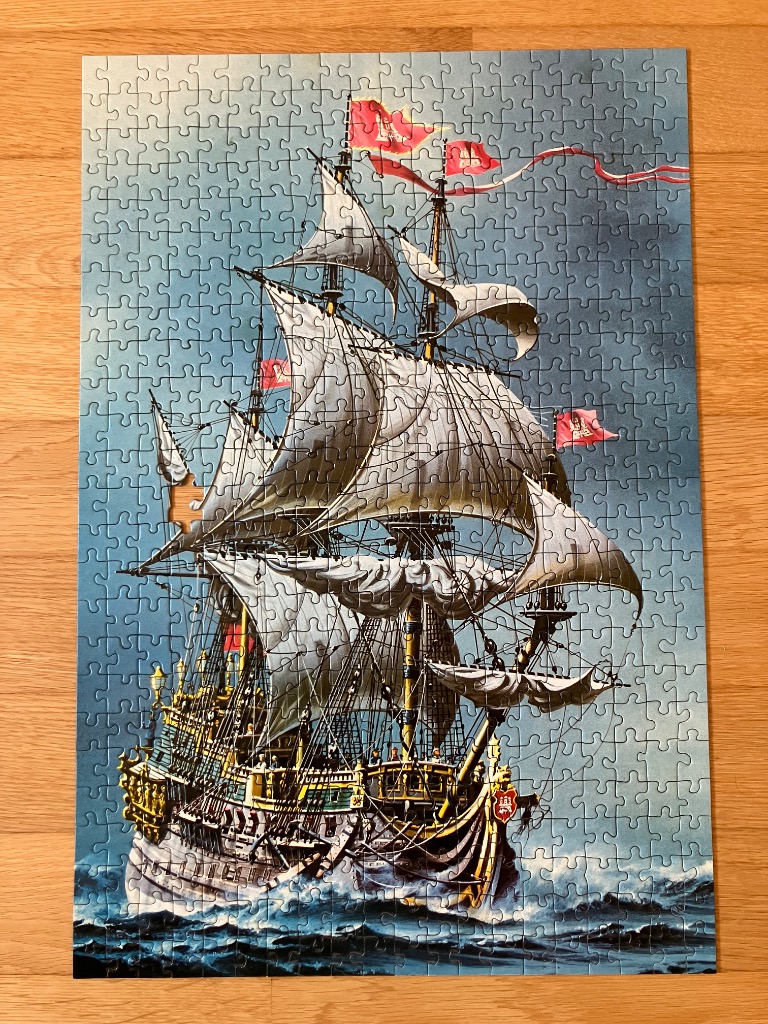 A detailed illustration of an ornate galleon sailing on rough, dark blue seas under a twilight sky.