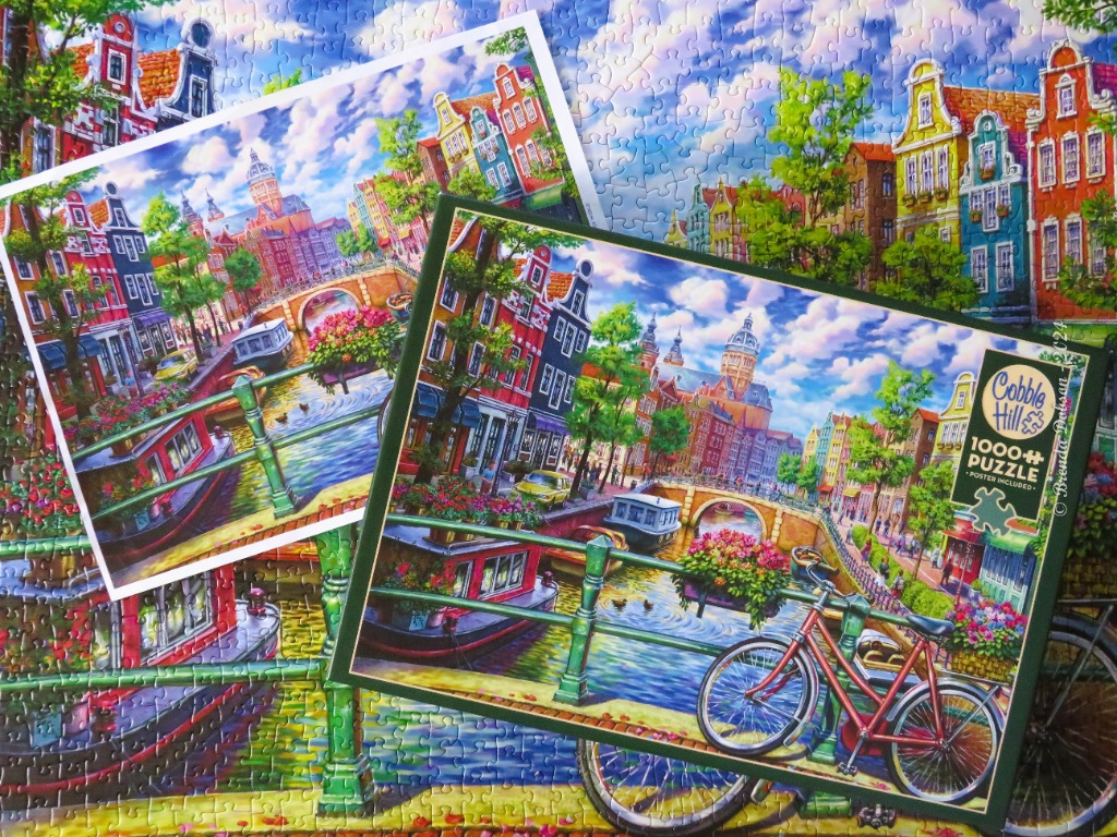 A scenic view of a European canal city with a red bicycle in the foreground.