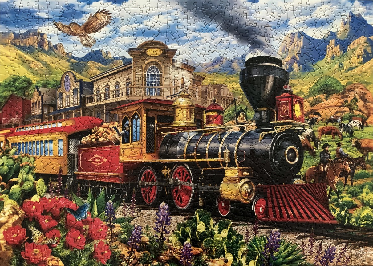 Old West scene featuring a steam train in front of a saloon with mountains in the background.