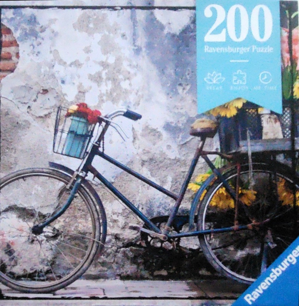 A vintage blue bicycle with a flower-filled basket parked against a weathered, textured stone wall.