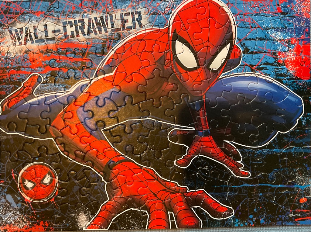 A dynamic illustration of Spider-Man crouching over a graffiti-style urban background with the text WALL-CRAWLER.