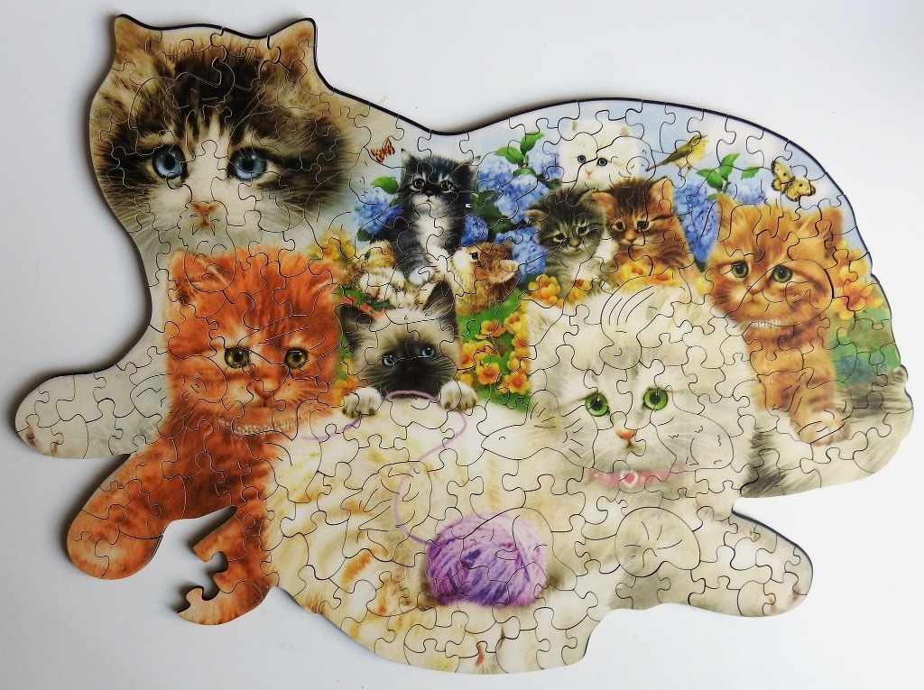 A whimsical shaped cat-silhouette collage filled with various kittens and a yarn ball.