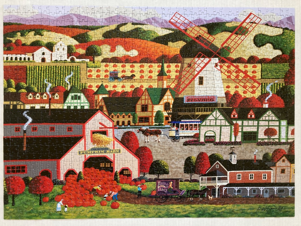 Folk art scene of a pumpkin harvest in a Danish-style village with a windmill, farm buildings, and rolling hills.