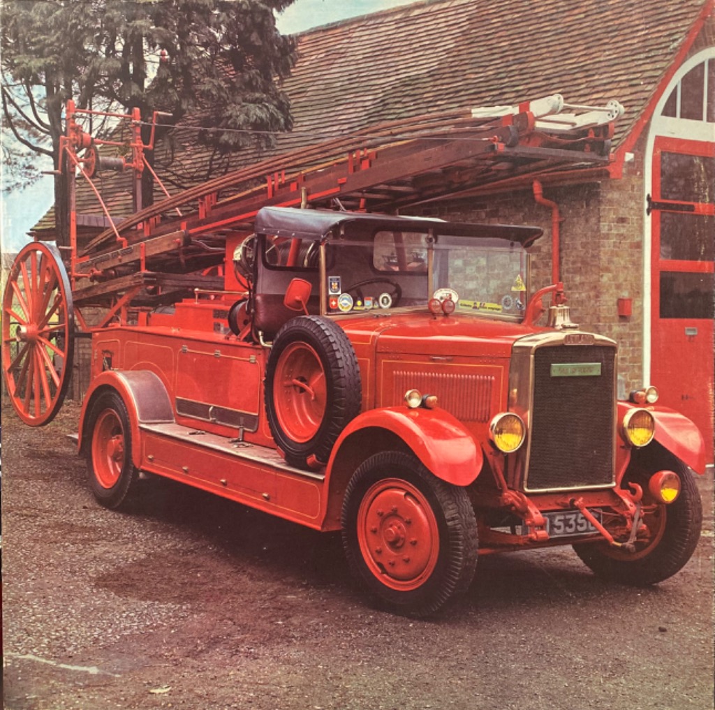 A vintage bright red fire engine parked in front of a brick building