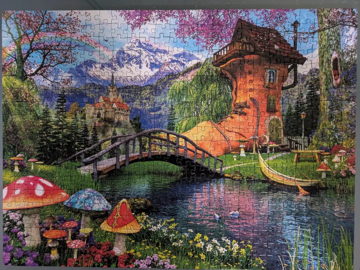 A whimsical fairytale landscape featuring a shoe-shaped house, a castle in the mountains, and oversized mushrooms.