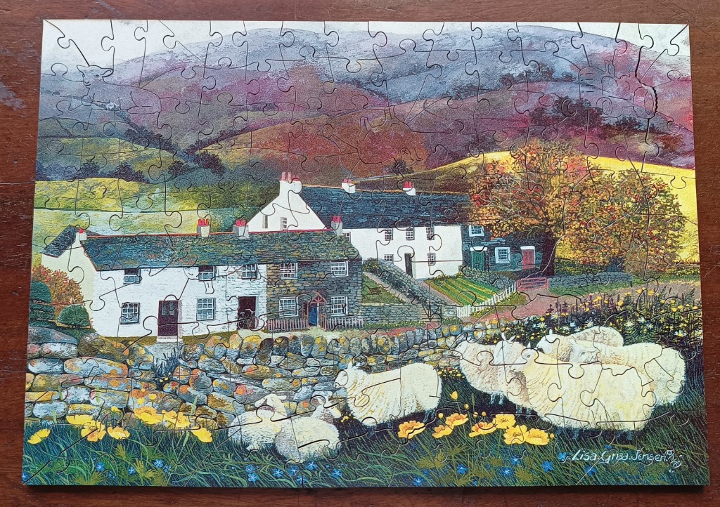 A countryside illustration of white cottages with stone walls and sheep grazing in the foreground under rolling hills.