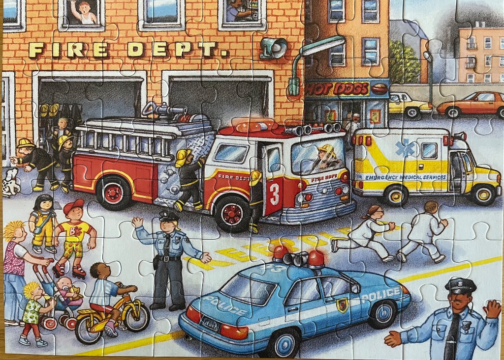 A busy city scene with a fire station, police cars, and an ambulance featuring emergency responders and local pedestrians.