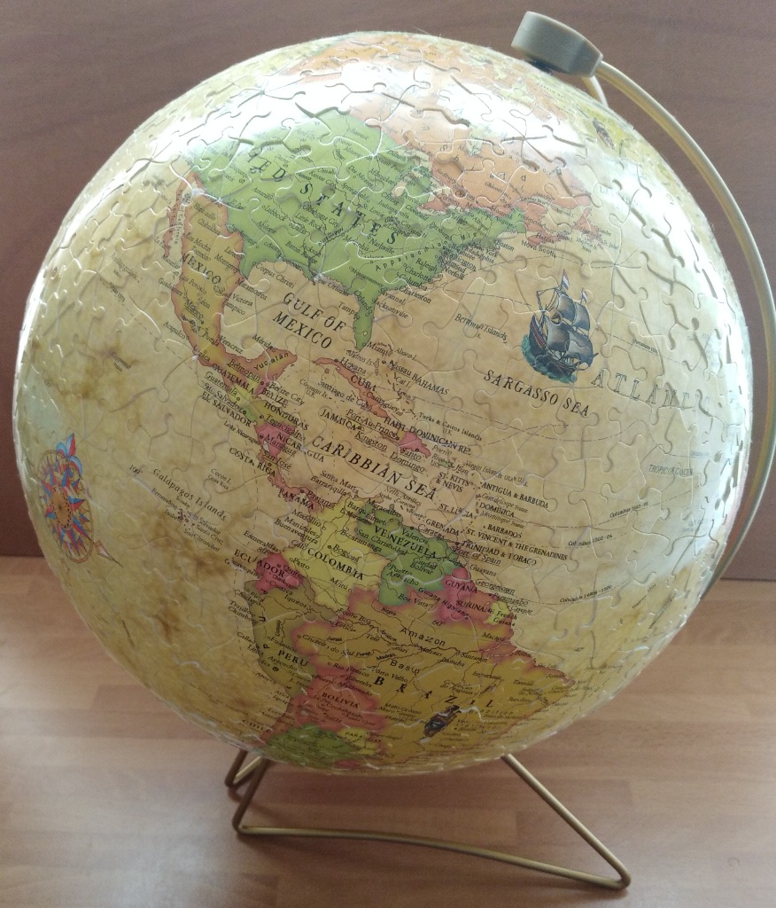 A spherical globe on a stand showing North and South America in an antique parchment style.