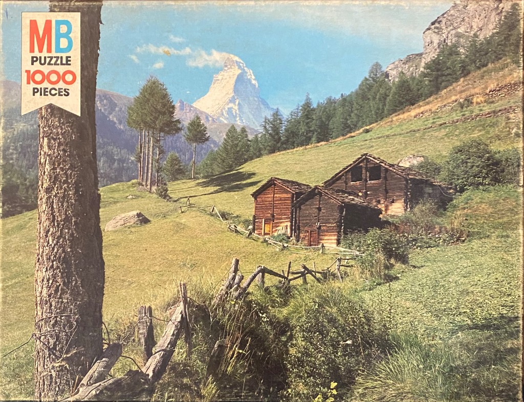 Alpine landscape with rustic wooden barns in the foreground and the Matterhorn in the background.