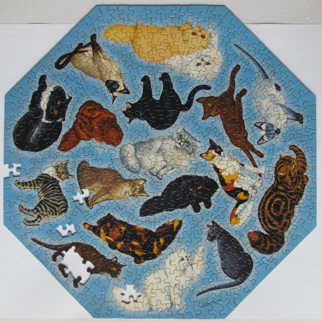 An octagonal image featuring many different breeds of cats floating against a plain light blue background.