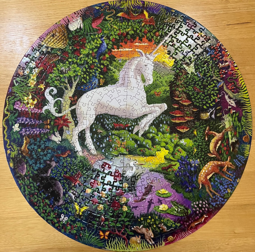 A circular illustration featuring a white unicorn in a vibrant, lush forest filled with various woodland animals.