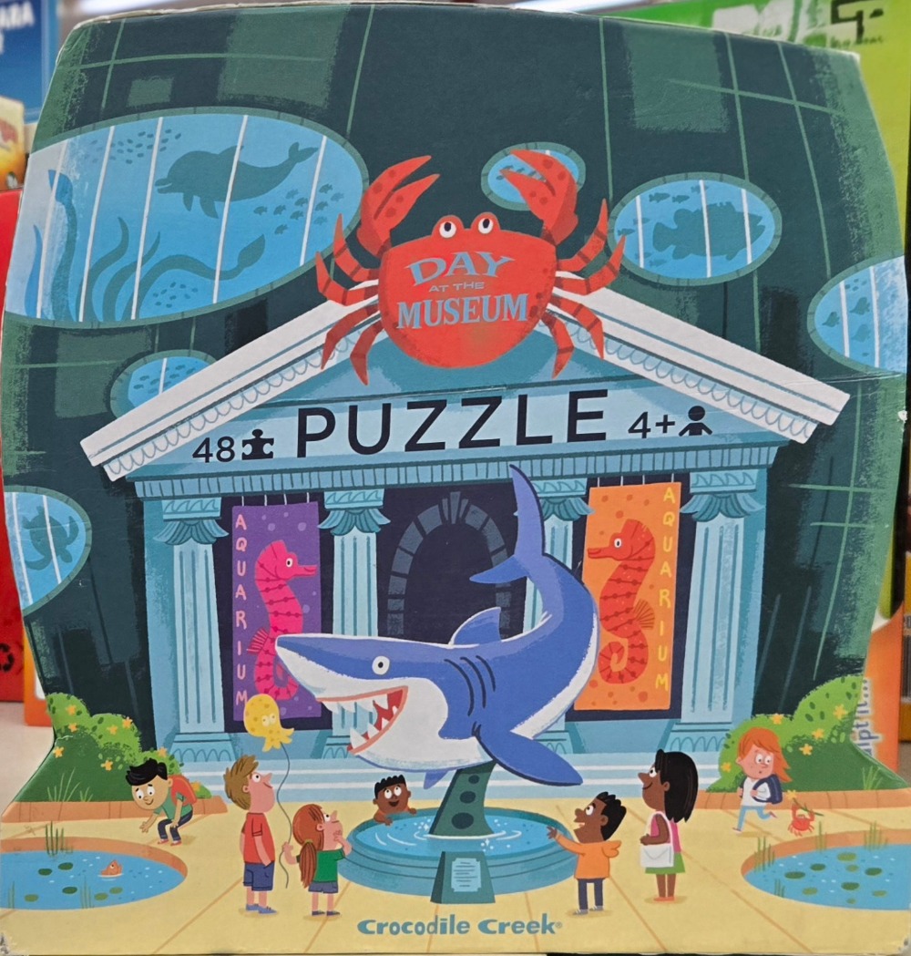 An illustration of a child-friendly aquarium museum building with a shark fountain and curious children outside.