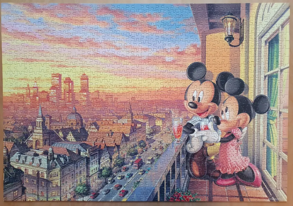 Mickey and Minnie Mouse on a balcony overlooking a city skyline at sunset.