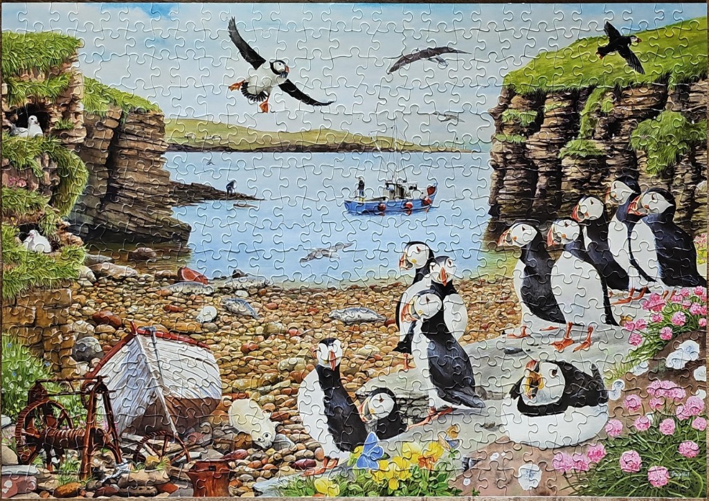 A coastal scene featuring many puffins on a rocky shore with cliffs, a small boat, and flowers.