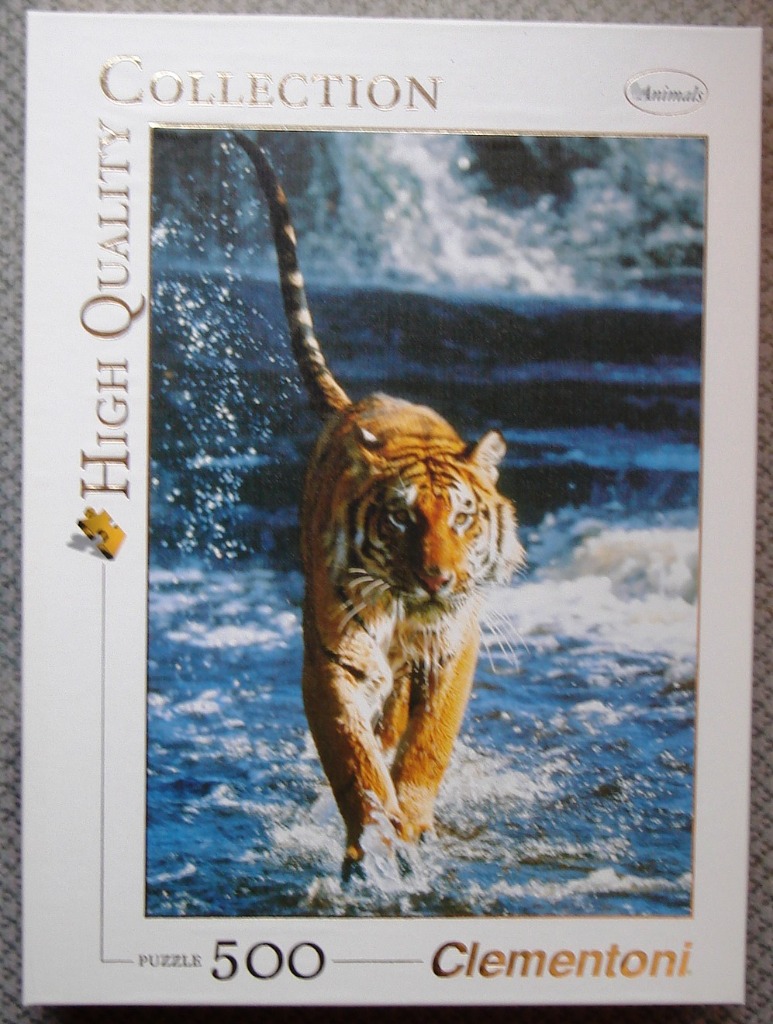 A tiger walking through shallow, rushing blue water, splashing as it moves.