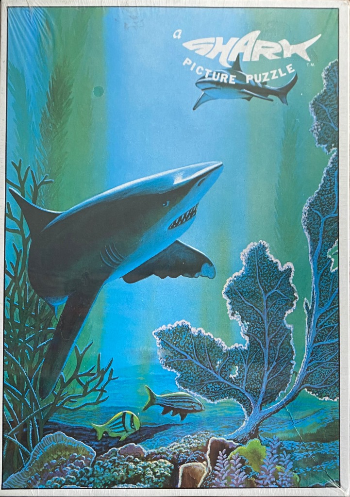 An underwater scene featuring a large shark swimming past coral and smaller fish.