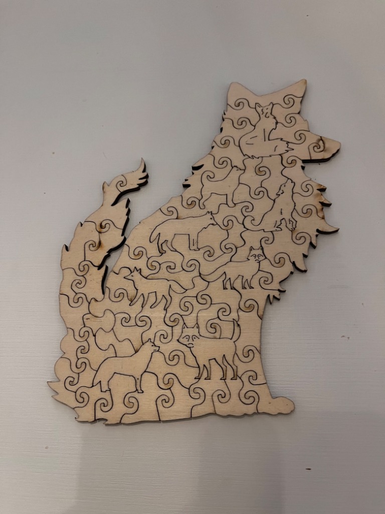 A silhouette of a sitting wolf carved from wood, featuring patterns of smaller wolves within its outline.